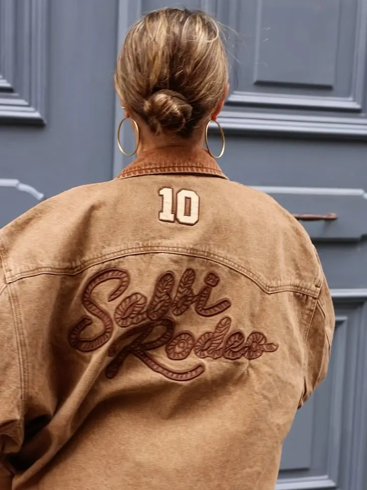 Rugzijde van de bruine jas met geborduurde Sabbi Rodeo-letters en het nummer 10
