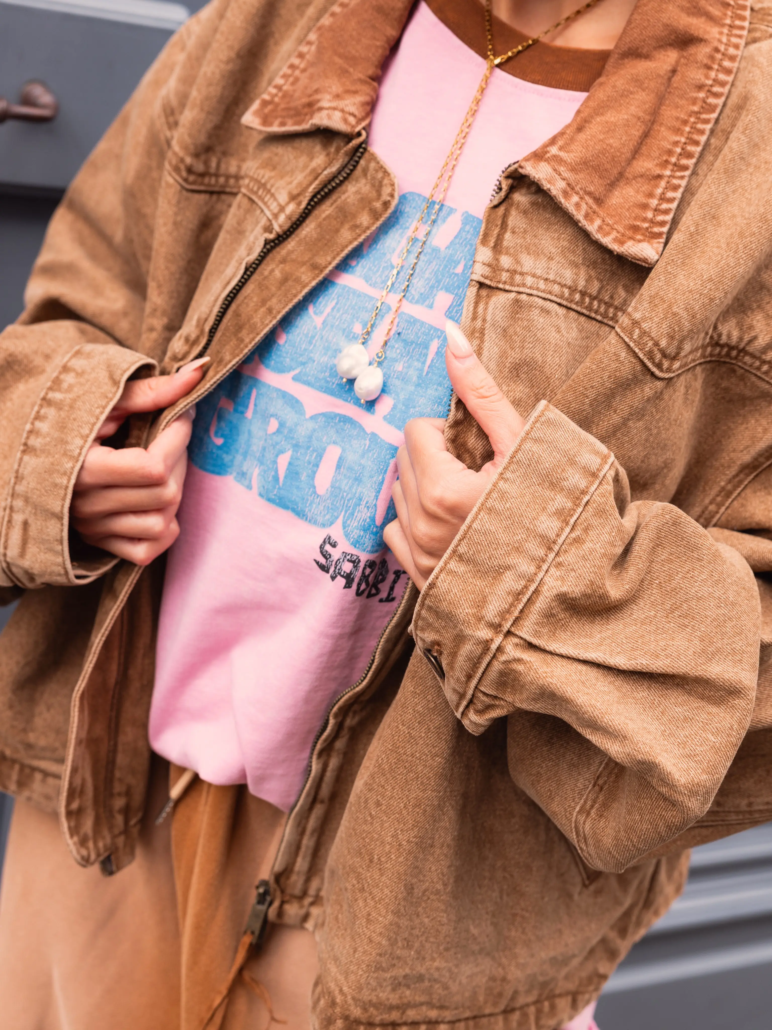 Close-up van de open bruine jas met een roze shirt eronder