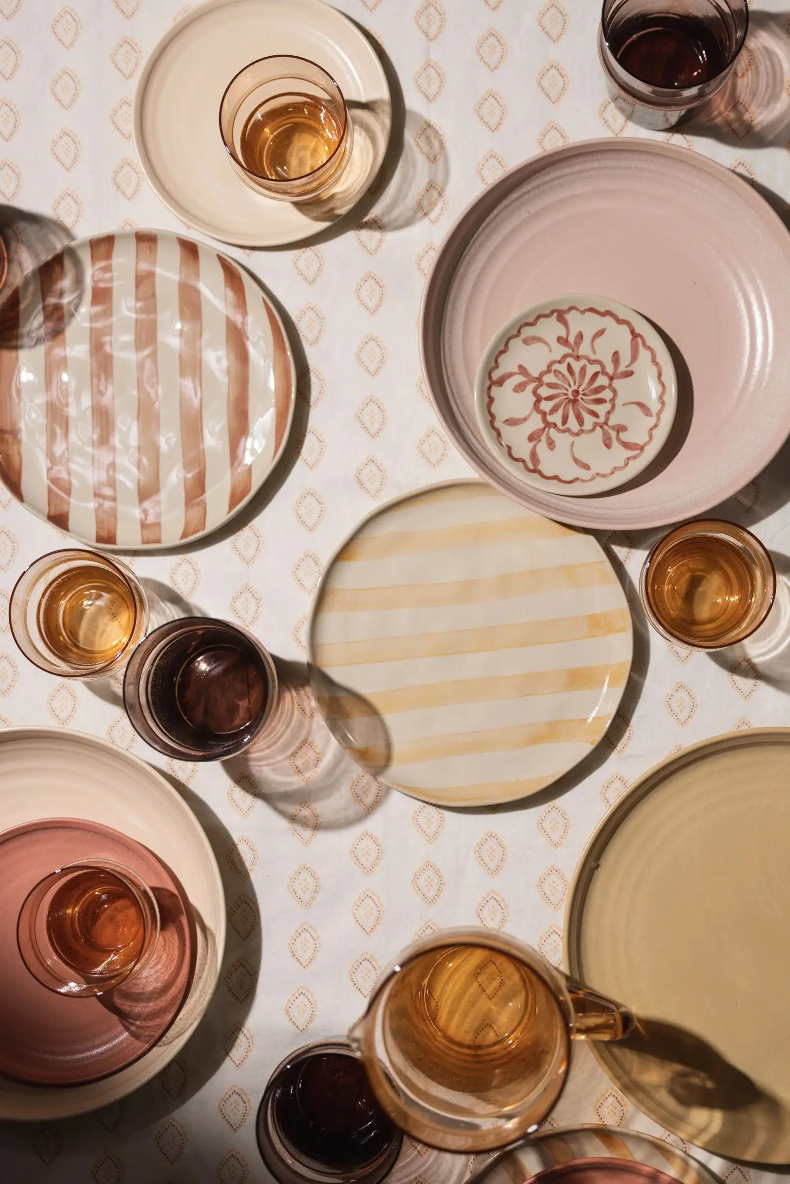 Bovenaanzicht van een gedekte tafel met gestreepte en gekleurde borden en glazen